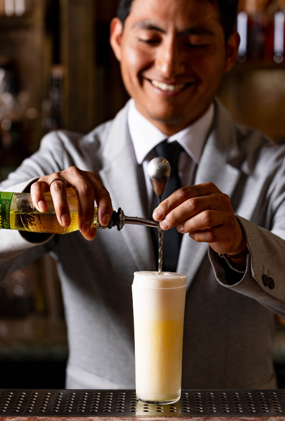 A smiling bartender finishing a fizz in the afternoon